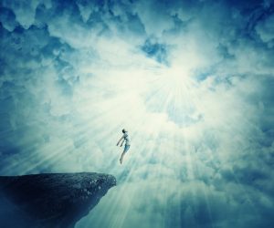 Energy healing can raise our vibration. Man hovering over cliff like he is flying.
